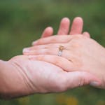 Close-up of a romantic proposal featuring a citrine engagement ring held gently outdoors.
